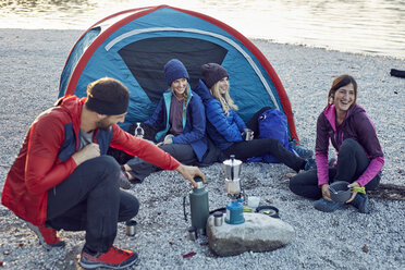 Group of hikers camping at lakeshore at sunset - PNEF00504