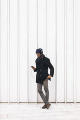 Italien, Mailand, afroamerikanischer Mann mit Smartphone und Kopfhörer - MAUF01277