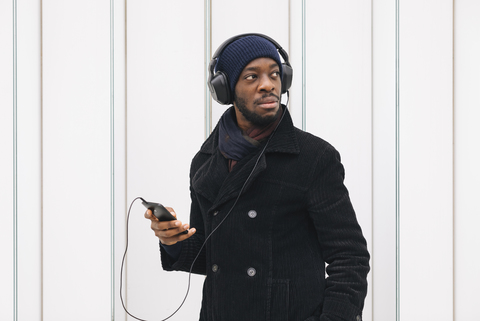 Italien, Mailand, afroamerikanischer Mann mit Smartphone und Kopfhörer, lizenzfreies Stockfoto