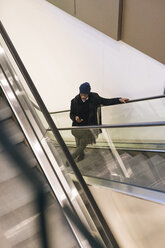 Italien, Mailand, Afroamerikanischer Mann mit Smartphone auf Rolltreppe - MAUF01288