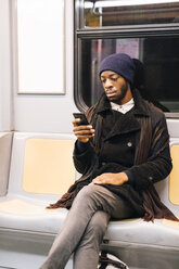 Afroamerikanischer Mann mit Smartphone in der U-Bahn - MAUF01297