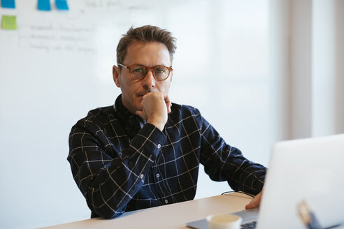 Porträt eines seriösen Geschäftsmannes mit Laptop am Schreibtisch im Büro - EBSF02080