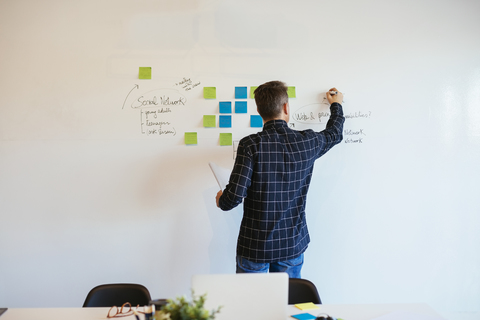 Businessman in office writing on whiteboard stock photo