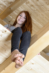 Porträt eines lachenden rothaarigen Teenagers auf einem Dachboden - LBF01758