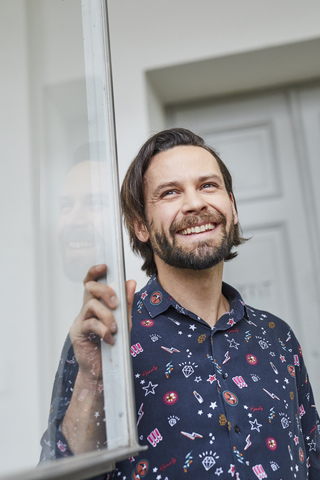 Porträt eines lachenden Mannes am offenen Fenster, lizenzfreies Stockfoto