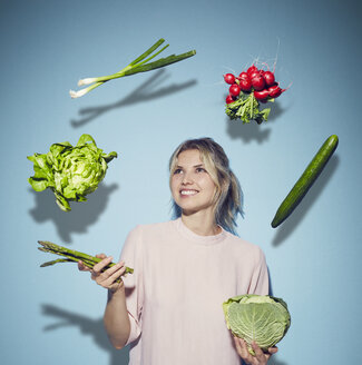 Portrait of happy young woman juggling with vegetables - PNEF00518