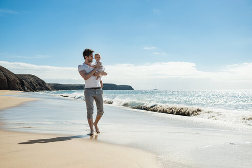 Spanien, Lanzarote, Vater trägt seine kleine Tochter am Strand - DIGF03224