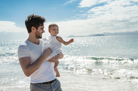 Spanien, Lanzarote, Vater trägt seine kleine Tochter am Strand, lizenzfreies Stockfoto