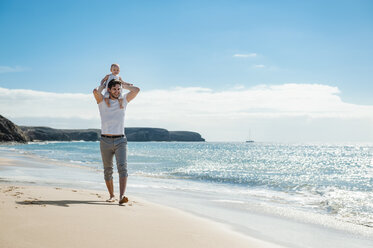 Spain, Lanzarote, father carrying little daughter on his shoulders on the beach - DIGF03226