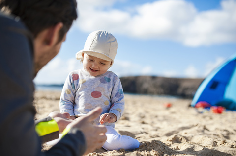 Spanien, Lanzarote, glückliches kleines Mädchen, das mit seinem Vater am Strand spielt, lizenzfreies Stockfoto