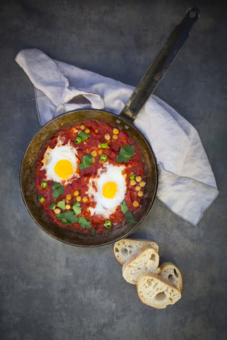 Shakshouka with chick peas in pan and slices of baguette stock photo