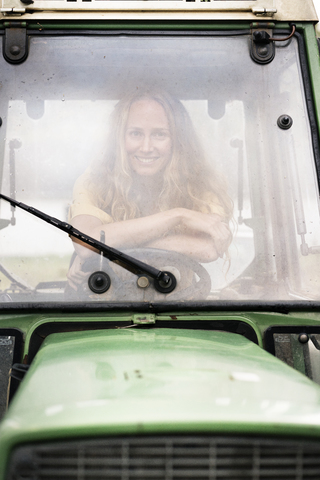 Porträt einer lächelnden Frau, die in einem Traktor sitzt, lizenzfreies Stockfoto