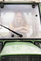 Porträt einer lächelnden Frau, die in einem Traktor sitzt - PESF00941