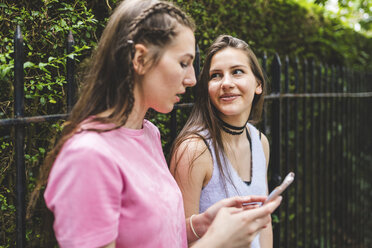 Zwei Mädchen im Teenageralter mit Mobiltelefon im Freien - WPEF00002