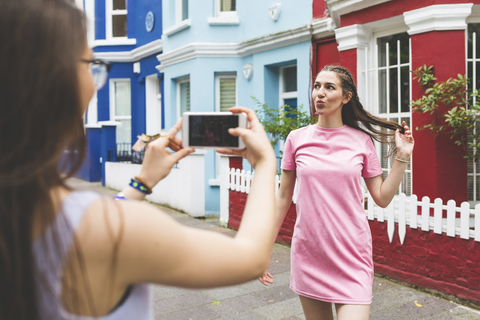 Teenager-Mädchen nimmt Handy-Foto von junger Frau in der Stadt, lizenzfreies Stockfoto