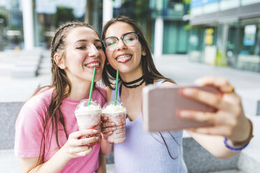 Two happy teenage girls drinking milkshakes in the city taking a selfie - WPEF00028