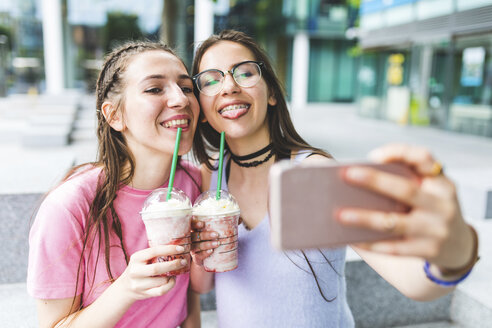 Zwei glückliche Teenager-Mädchen trinken Milchshakes in der Stadt und machen ein Selfie - WPEF00028