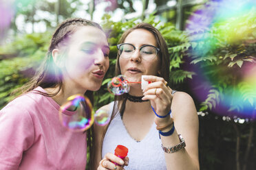 Zwei Mädchen im Teenageralter blasen gemeinsam Seifenblasen - WPEF00032