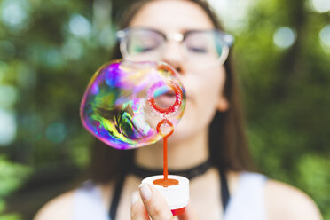 Teenage girl blowing soap bubbles outdoors - WPEF00034