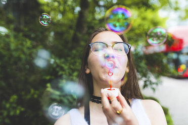 Teenage girl blowing soap bubbles outdoors - WPEF00035