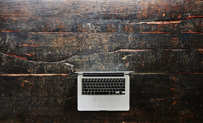 Laptop auf dunklem Holz, Ansicht von oben - FMKF04781