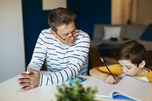 Vater beobachtet Sohn bei den Hausaufgaben am Tisch - EBSF02118