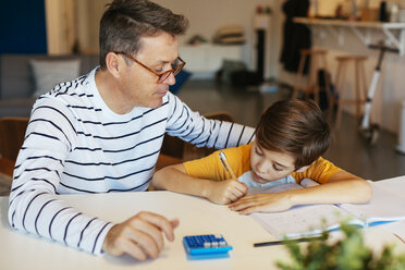 Vater beobachtet Sohn bei den Hausaufgaben am Tisch - EBSF02119