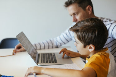 Vater und Sohn an einem Tisch mit einem Jungen, der einen Laptop benutzt - EBSF02121