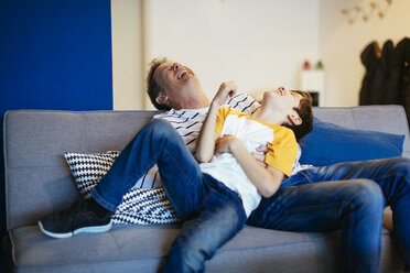 Carefree father and son having fun on couch at home - EBSF02126
