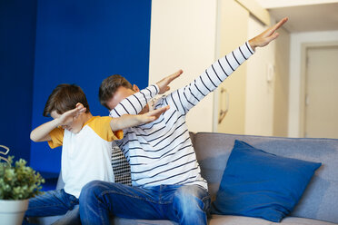 Father and son making a dab on couch at home - EBSF02128