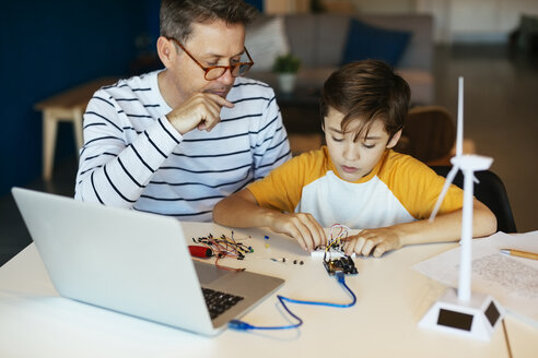 Vater und Sohn beim Zusammenbau eines Baukastens mit Laptop und Windradmodell - EBSF02129