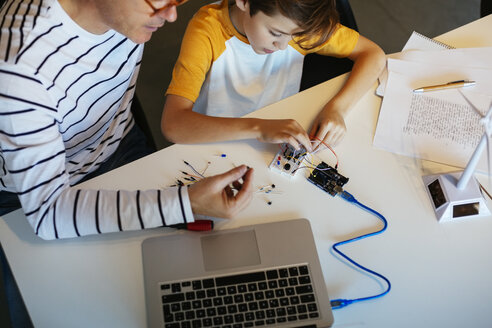 Vater und Sohn beim Zusammenbau eines Baukastens mit Laptop und Windradmodell - EBSF02131