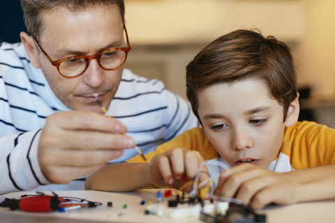 Father and son assembling an electronic construction kit stock photo