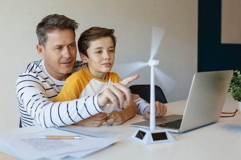 Father and son with laptop testing wind turbine model stock photo