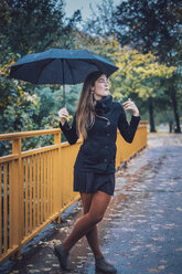 Junge Frau mit Regenschirm steht auf einer Brücke im Herbst - JSCF00033