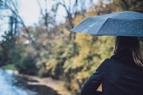 Rückenansicht einer jungen Frau mit nassem Regenschirm im Herbst - JSCF00035