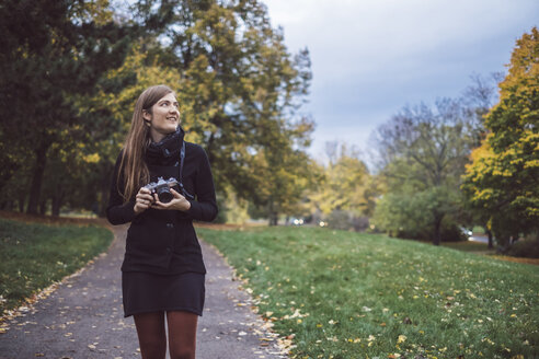 Junge Frau mit Kamera bei einem Spaziergang in einem herbstlichen Park - JSCF00046