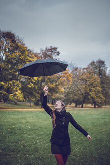 Glückliche junge Frau tanzt mit Regenschirm im herbstlichen Park - JSCF00052