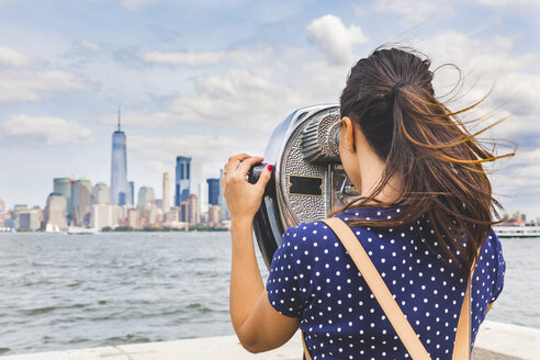 USA, New York, Frau betrachtet die Skyline von Manhattan mit einem münzbetätigten Fernglas - WPEF00046