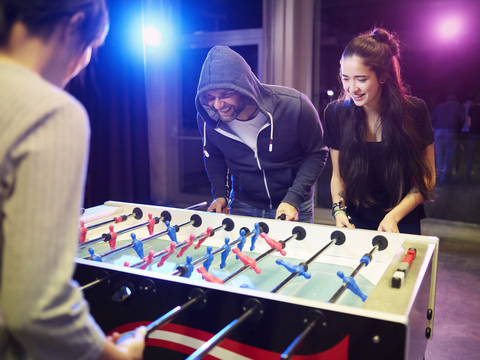 Glückliche Freunde spielen Tischfußball, lizenzfreies Stockfoto