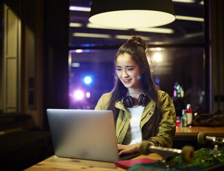 Lächelnde junge Frau mit Laptop auf dem Tisch - CVF00105