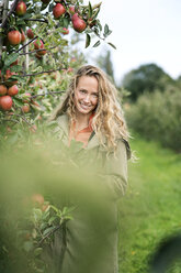 Portrait of smiling woman in apple orchard - PESF00950
