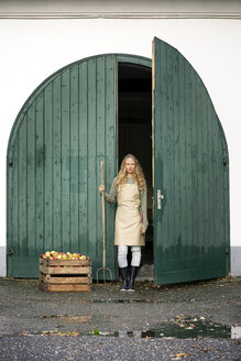 Frau auf einem Bauernhof stehend an Kiste mit Äpfeln - PESF00967