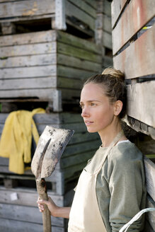 Thoughtful woman leaning against wooden boxes - PESF00972