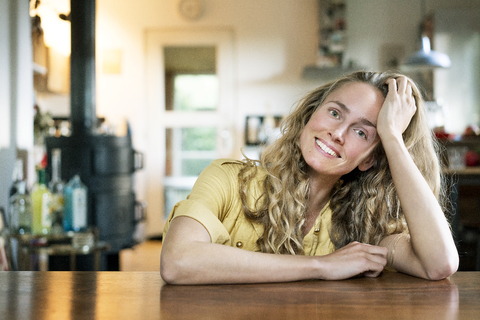 Portrait of smiling blond woman leaning on table stock photo