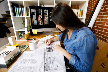 Junge Frau arbeitet in einem Architekturbüro und zeichnet Entwürfe - VABF01457