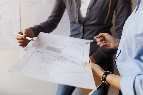 Female architects working on a project, looking at blueprint stock photo