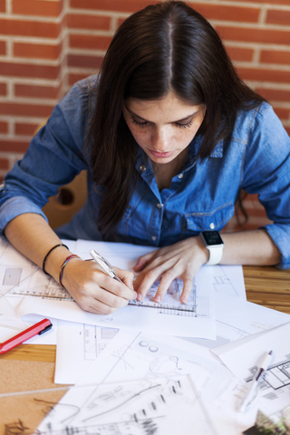 Junge Frau arbeitet in einem Architekturbüro und zeichnet Entwürfe, lizenzfreies Stockfoto