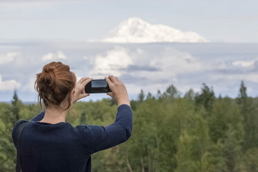 USA, Alaska, junge Frau fotografiert mit Smartphone Mount Denali - MMAF00273
