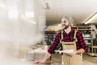 Glücklicher Arbeiter mit Entwurf in der Werkstatt - UUF12664